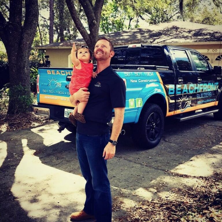 David Shoultz holding his daughter in front of a branded Beachfront Builders truck